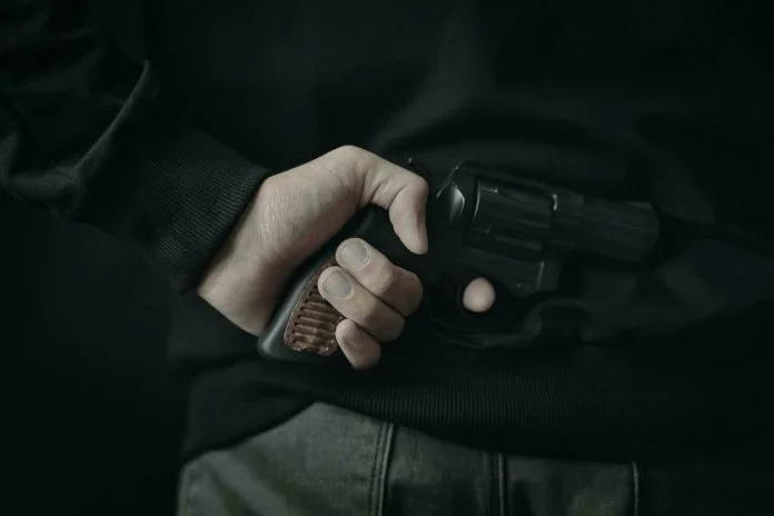 a-man-with-a-revolver-behind-his-back-photo-1-696x464